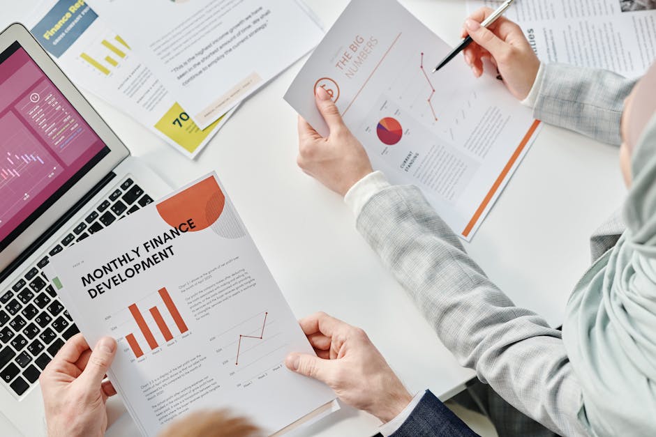 Uśmiechnięta osoba analizująca wykresy finansowe na laptopie w nowoczesnym biurze.